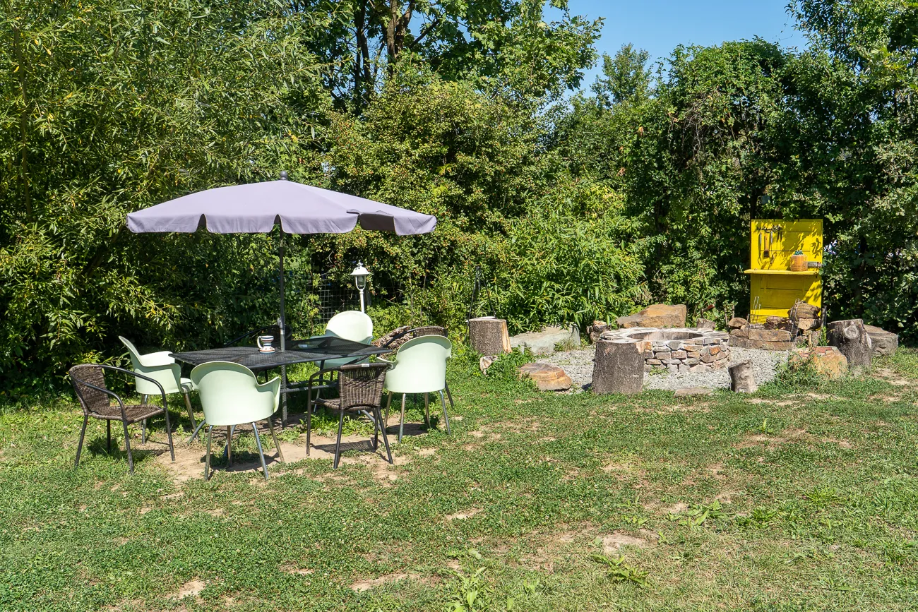 Grüner Rasen mit Tisch, Stühlen und Sonnenschirm unter Bäumen