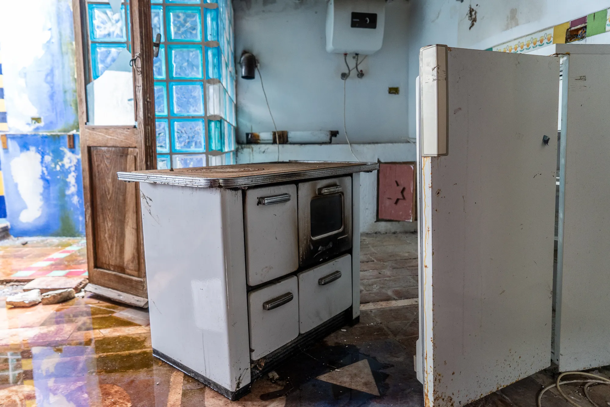 Verlassene Küche mit Backofen und Kühlschrank in einem verfallenen Raum