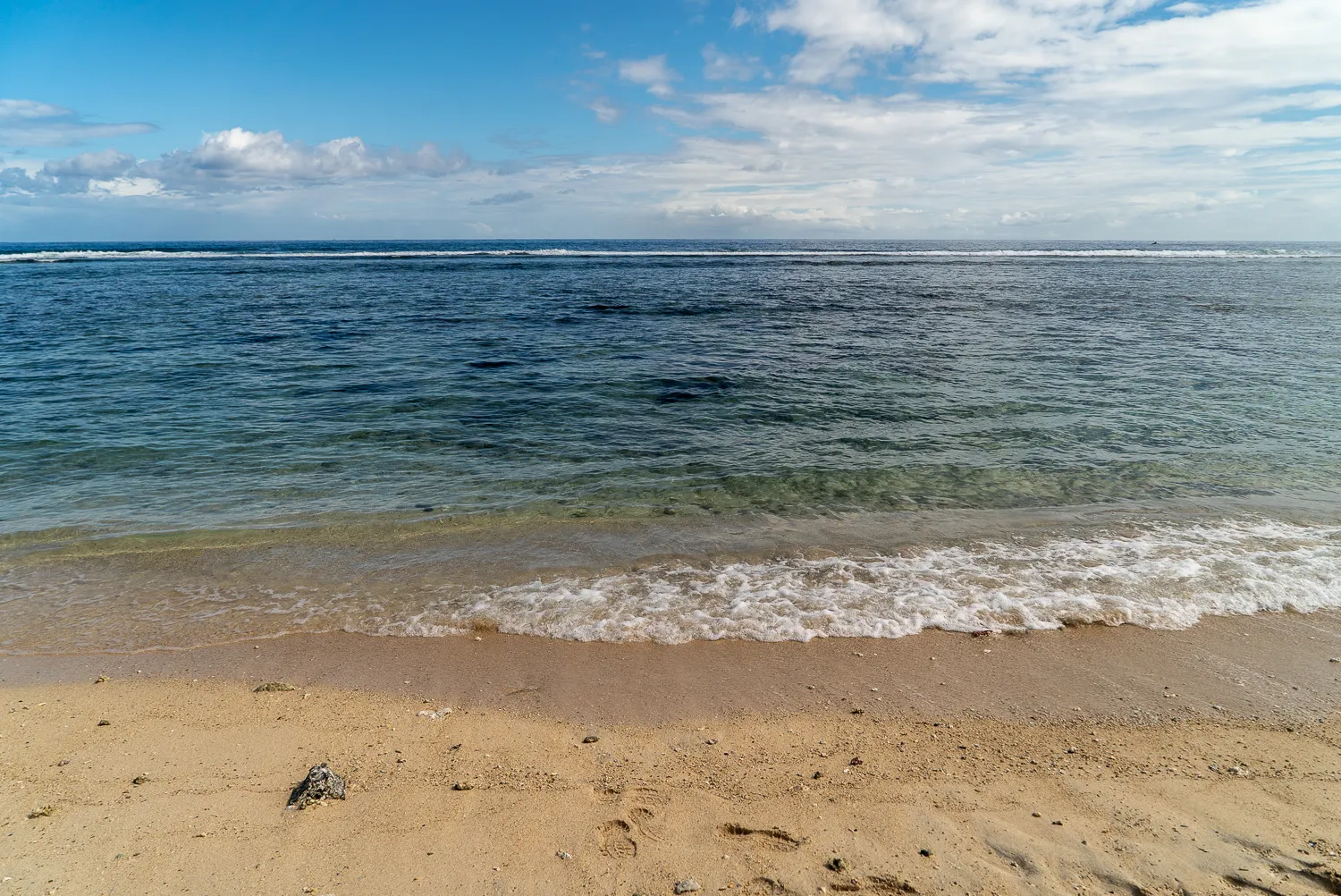 Strand mit sanften Wellen und blauem Himmel